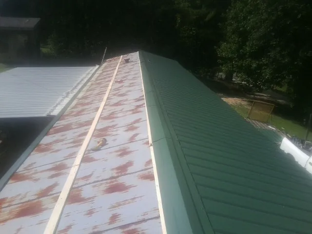 Old rusted panels beside newly installed green metal roofing — Wind Damage Roof Repair by Roofing Brothers in New Florence