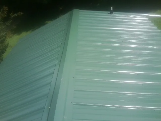 New green metal panels meeting at the ridge of a roof — Flat Roof Repair work by our crew in New Florence