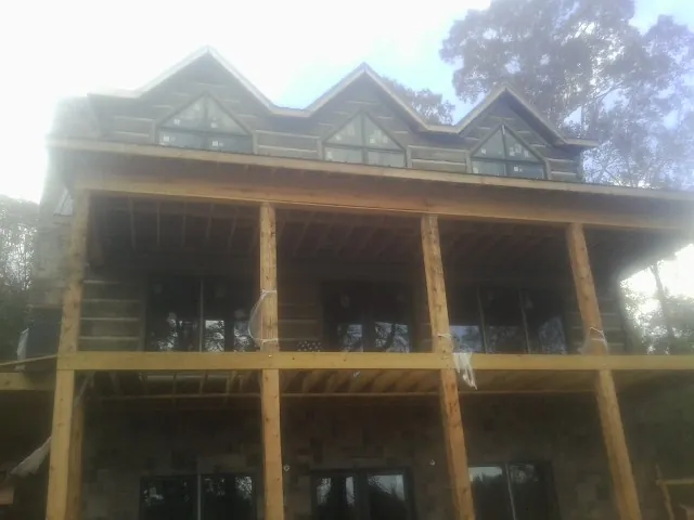 Dormers and porch framing on a large log home under construction — Roof Coating work by our crew in New Florence