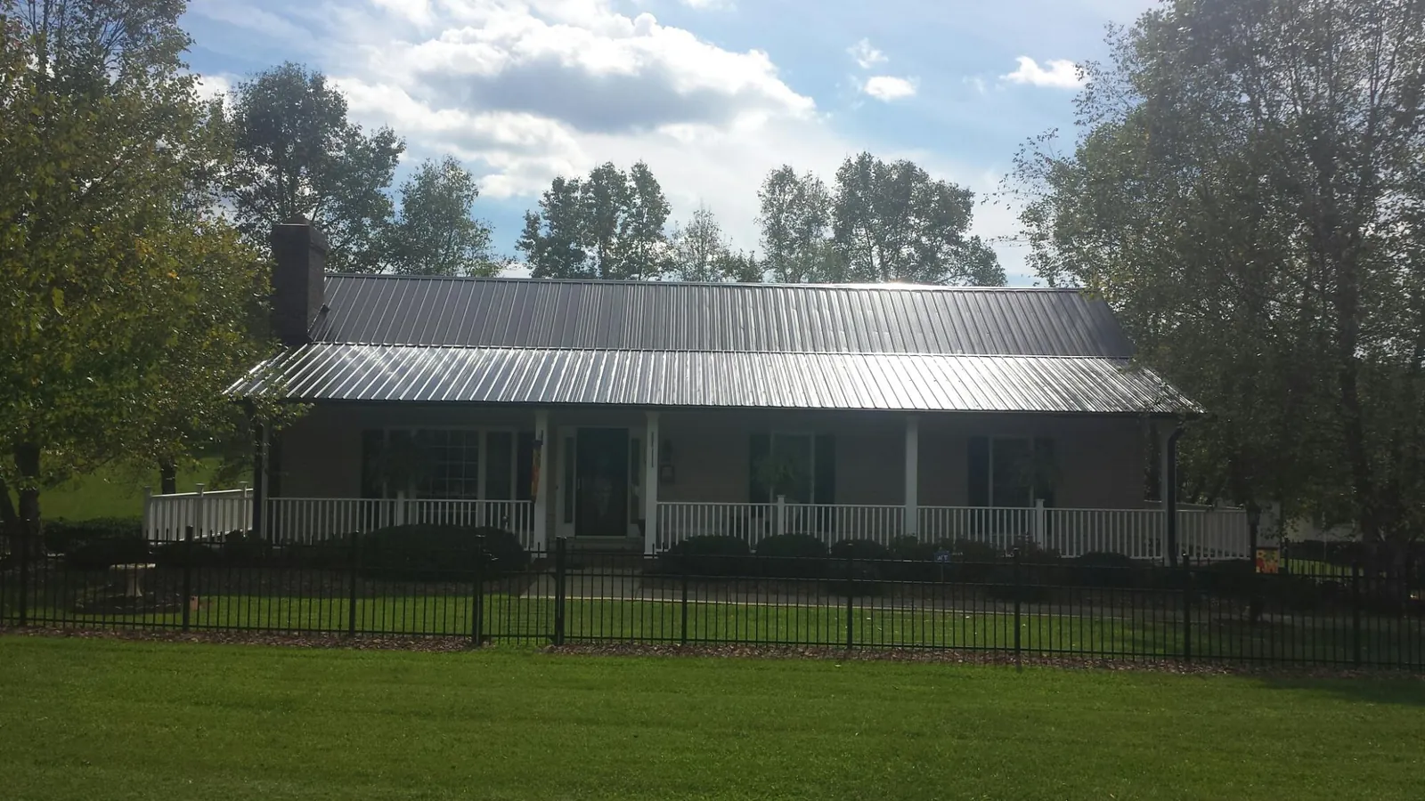 Gray metal roof on a brick ranch with a full width front porch — Gutter Guard Installation work by our crew in New Florence